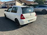La voiture blanche est garée sur le parking à côté de la maison.