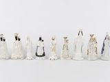 a group of seven figurines of people dressed in white and gold