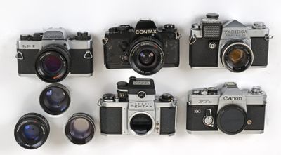 many cameras that are lined up together on a white surface