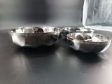 two metal bowls sitting on a table next to each other