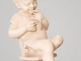 statue d'un enfant assis sur un socle, les mains posées sur la poitrine