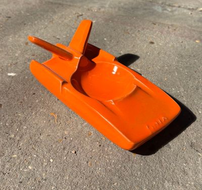 un petit bateau en plastique orange posé par terre