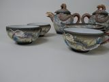 five different bowls and a teapot on a white table