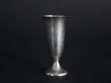 silver metal vase on a black surface with a black background