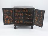 une petite armoire noire ornée d'un motif floral