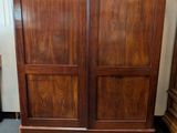 a wooden armoire in a room with a chandelier