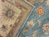 two blue and beige rugs on a wooden floor with a cat laying on top of them