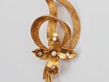 une photo d'une broche en forme de fleur en or ornée de perles