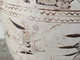 a white vase with brown designs on it sitting on a table