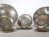 four pieces of silverware on stands on a white surface
