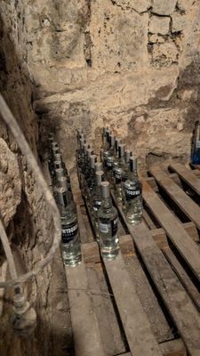 bottles of vodka are lined up on wooden pallets in a cave