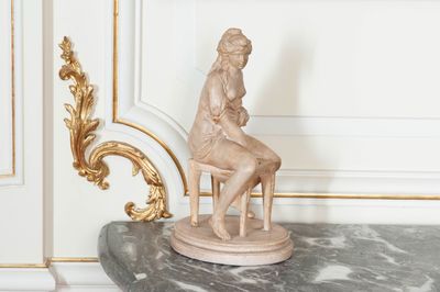 a statue of a woman sitting on a chair in a room