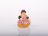 a small figurine of a woman in a pink dress