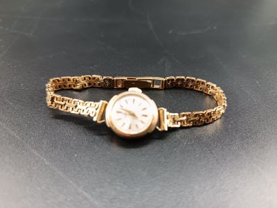 un bracelet en or avec une montre, posé sur une table