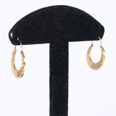 a close up of a pair of gold hoop earrings on a black stand