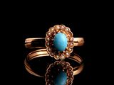 gros plan d'une bague en or avec une pierre turquoise