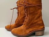 Bottes à lacets de couleur beige posées sur une surface blanche, avec un fond blanc