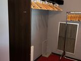 a room with a red carpet and a closet with clothes on hangers