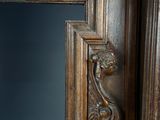 an antique mirror with a carved wood frame and a carved lion head