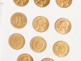 a lot of gold coins on a white surface next to a calculator