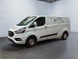 La camionnette blanche est garée dans une grande pièce au sol noir.