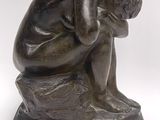 bronze statue of a man sitting on a rock with his head in his hands