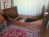 un lit avec un cadre en bois et un tapis rouge posé à même le sol