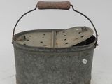 an old metal bucket with a wooden handle sitting on a white surface