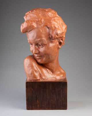 a bronze bust of a man with his head resting on a wooden block