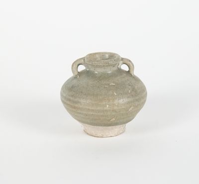 un vase gris muni de deux anses, posé sur une surface blanche