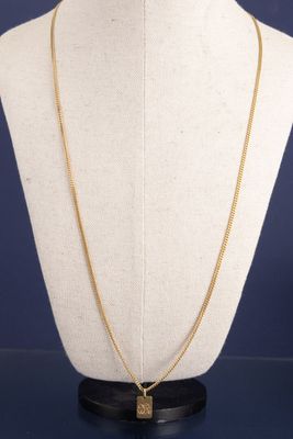 un collier en or avec un pendentif carré autour du cou d'un mannequin