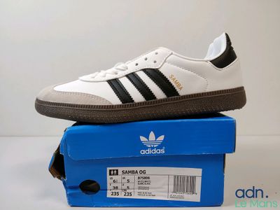 a white and black adidas sneakers on top of a blue box