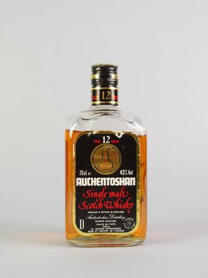 une photo d'une bouteille de whisky posée sur une surface blanche