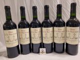six bottles of wine are lined up in a row on a table