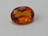Gros plan sur un saphir orange posé sur une surface blanche