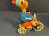 two toy clowns sitting on top of a toy bike