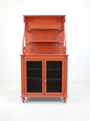 an orange cabinet with a glass door and a shelf on top of it