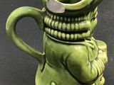 a green ceramic pitcher with a face on it