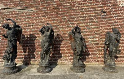 three statues of women are standing in front of a brick wall