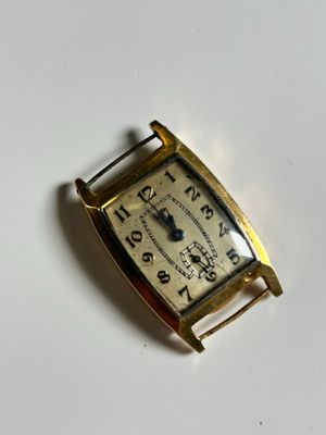 a small gold wrist watch on a white surface