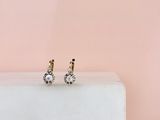 une paire de boucles d'oreilles en diamant posée sur un bloc de marbre blanc