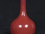 an old red vase sitting on a black surface with a black background