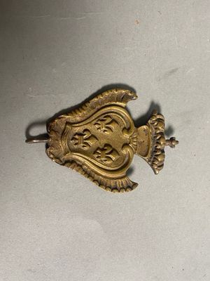 une broche en or posée sur une table avec un fond blanc
