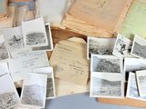 a pile of old photographs on a table next to a pair of scissors