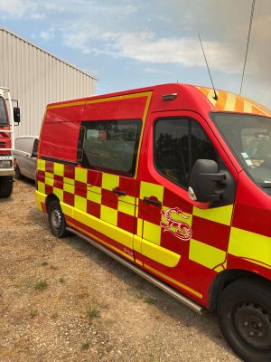 un camion de pompiers rouge et jaune garé à côté d'un camion de pompiers blanc