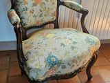 a chair with a floral upholstered seat in front of a window