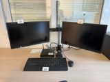 two monitors and a keyboard on a desk in front of a window