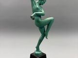 une statue verte représentant une femme tenant une fleur à la main