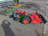un tracteur rouge équipé d'une débroussailleuse verte et rouge