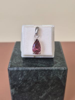 a close up of a pink stone pendant on a white box